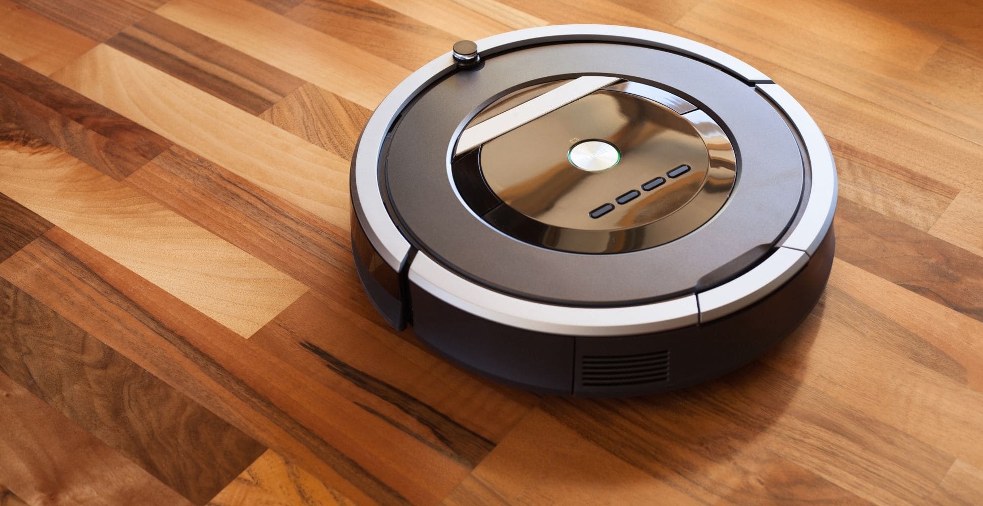 black and white robot vacuum cleaning on light brown hardwood floors - image by spruceup