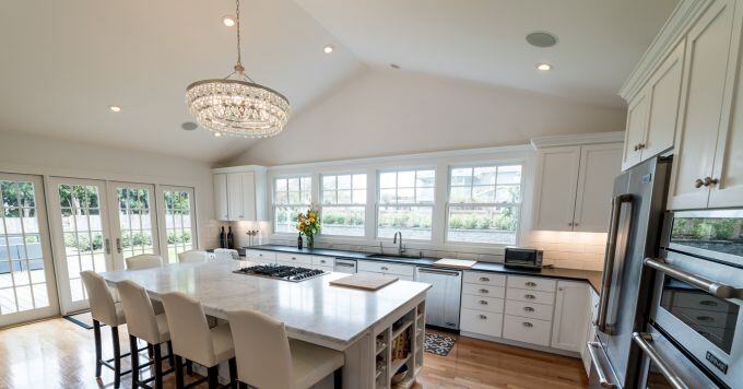 white kitchen with marble island and crystal chandelier