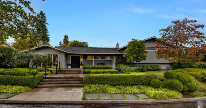The front yard of a home with a helpful handrail near the steps leading to the front door.